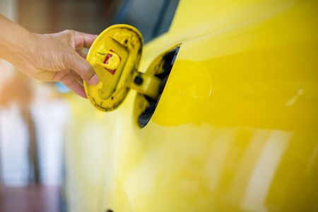 Hand close the oil filler cap of yellow car at the gas station. Hand open the yellow car's oil cap to refuel.の写真素材