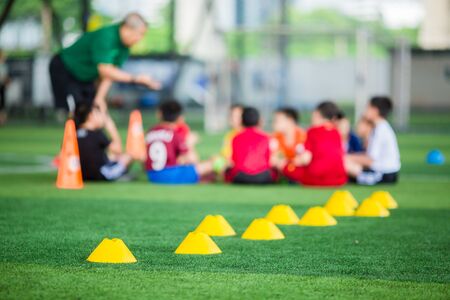 Selective focus to yellow cone markers are soccer training equipment on green artificial turf with...