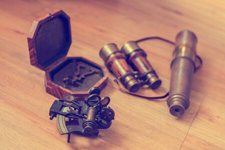 Vintage navigation equipment on wood background. Old Brass Theodolite, Wood pocket compass with cover lid, Old binoculars, old brass telescope, Traveling concept and vintage style.の写真素材