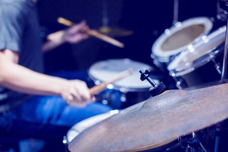 Young musicians wear t-shirts, jeans, and play the drum set and cymbals with wooden drumsticks in music room , the concept of musical instrument.の写真素材