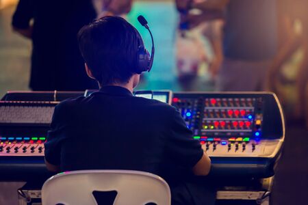 Technicians are controlling the sound system and lighting system on the concert stage. The sound...