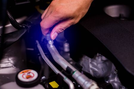 The hand of a mechanic is checking the connectors of car engine. Checking the engine by yourself....