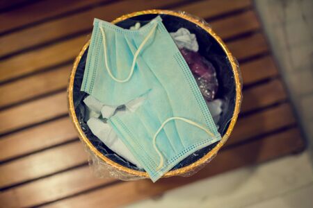 The used mask is cut to prevent reuse in the bucket. Close up of used face masks, medical face masks. Useless coronavirus face mask.の写真素材