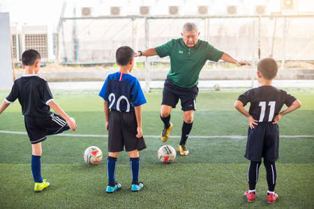 Bangkok , Thailand  - March 7, 2020 : Coach and kid soccer player are training football in TC Football Club Rama3, Bangkok.のeditorial素材
