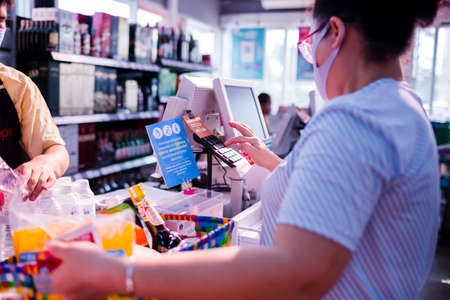 Bangkok, Thailand - March 29, 2020 : Asian women wear mask to prevent Coronavirus (Covid-19) and use baskets for plastic saving programs in supermarket. She pay for product at cashier counter.のeditorial素材