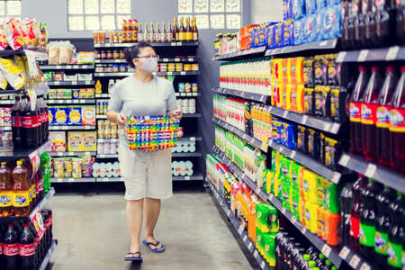 Bangkok, Thailand - March 29, 2020 : Asian women wear mask to prevent Coronavirus (Covid-19) and carry baskets for plastic saving programs in supermarket.のeditorial素材
