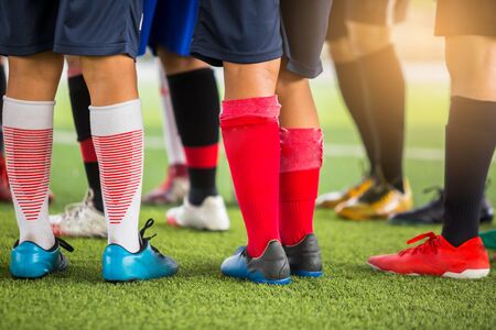 boy soccer players are put multi color sport shoes and standing on green artificial turf with coach...
