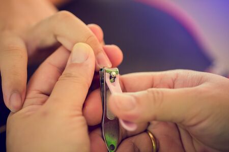 Selective focus to woman cutting nails to a hygiene child. Female hands hold nail scissors and child's hand. Manicure for kid by hand of scissor to cut nail for clean.の写真素材