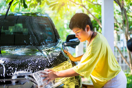 Asian boy is washing black car shampoo at home.の写真素材