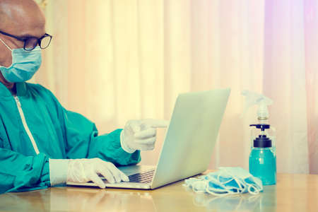 Selective focus to hand of Medical doctor or Psychologist is wearing mask and working with laptop in...