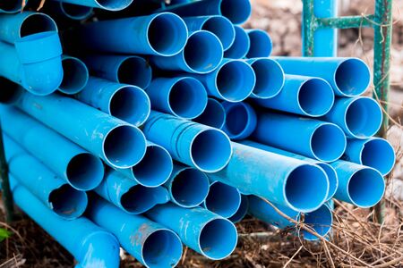 Selective to blue plastic pipe background. PVC pipes stacked in warehouse of construction site.  PVC water pipes used for construction.の写真素材