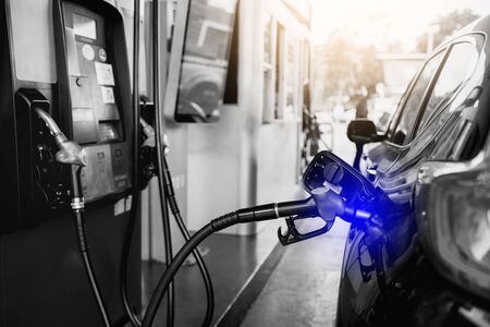 Selective focus to Petrol pump filling nozzles. Black car refueling on a petrol station. Pumping...