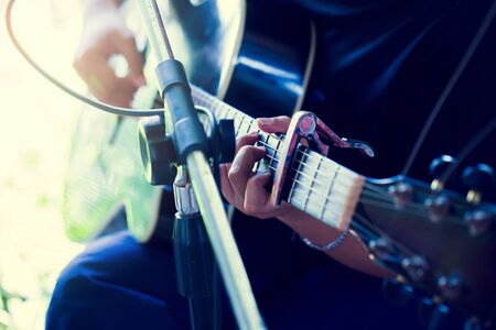 Selective focus to Asian woman's hands playing acoustic guitar. Close up girl musician's hands playing guitar at a live show on stage. The concept of musical instrument. の写真素材