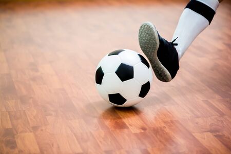 Indoor soccer sports hall. Football futsal player, ball, wooden futsal floor. Sports background. Youth futsal league. Indoor football players with classic soccer ball.の写真素材