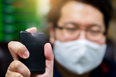 Hand is spraying alcohol with blurry businessman working in office. The concept of cleaning in...