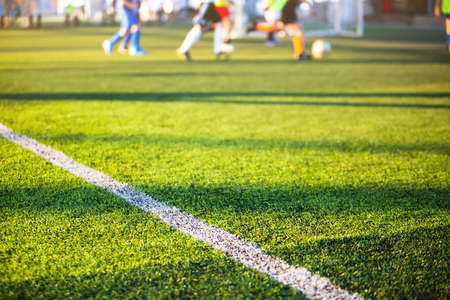Selective focus to white lines on green artificial grass football fields with kid soccer player....