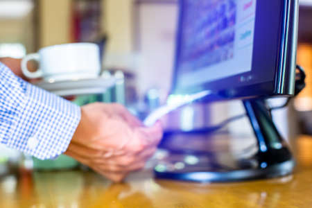Selective focus to  cashier is printing receipt at cashier machine and blur hold coffee cup for...