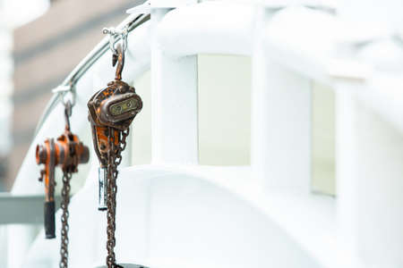 Selective focus to chain Hoist, Steel hook in construction site, Industrial hook hanging on white steel framework.の写真素材