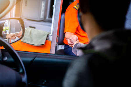 Selective focus to hand of driver pay for the expressway. Man pays money to a cashier for a toll...