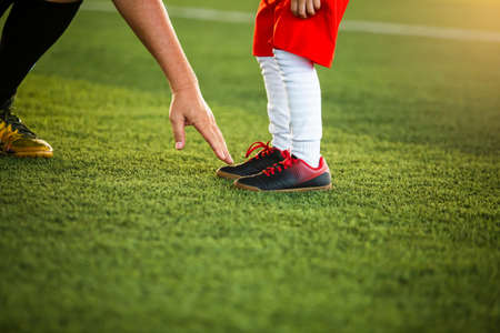 The coach is pointing the finger at the feet of a kid  soccer player to suggest playing soccer.の写真素材