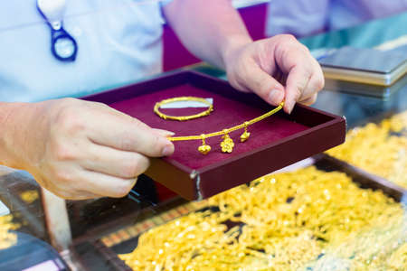 Selective focus to gold bracelet in hand, customer is buying gold jewelry in the gold shop at...