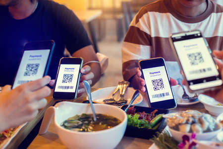 Selective focus to QR code tag and Barcode on smartphone in hands with blurry food and dessert in restaurant to accepted generate digital pay without money. QR code payment concept. Barcode Payment.の写真素材