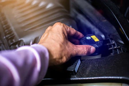 Selective focus to The mechanic's hand is opening the cap to check the brake fluid in the car engine...