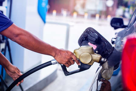 hand refilling the car with fuel at the gas  station, car in gas station, refilling the car with...