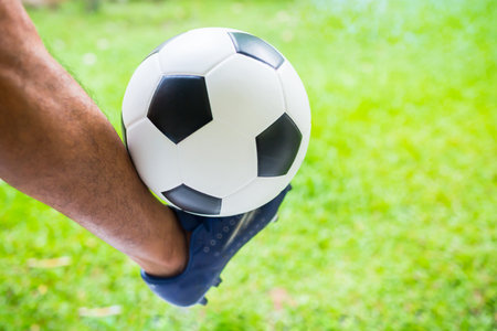 Soccer ball on leg with sport shoe of player on blurry green background.の写真素材