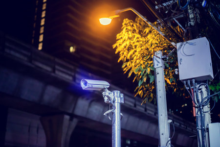 Selective focus to CCTV Camera with blurry lamp and modern building.