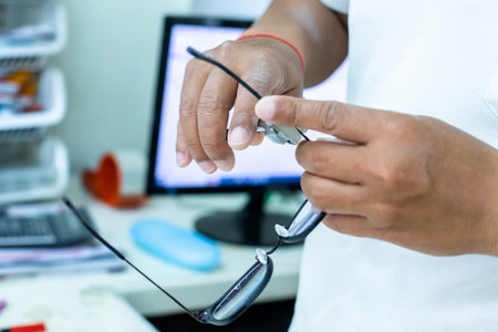 Selective focus to optician's hand bends the temples of glasses in eyeglass shops. Tools to help make glasses for patients.の写真素材