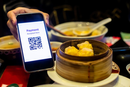 Customer hand using smart phone to scan QR code tag with blur dim sum or chinese food to accepted...