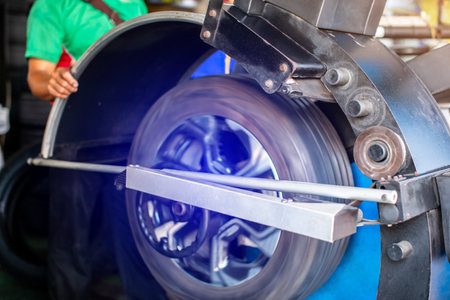 Selective focus to automobile machine setting the wheel balance center with blurry mechanic working. Technical man repairs, maintenance, and set the wheel center, check balance of wheel for safety.の写真素材