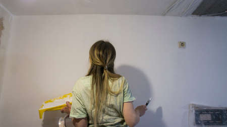 Renovation of the room, the girl performs painting work