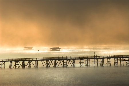 Silhouette of the wooden bridge in the mist Wooden bridge in the morning Bridge of the Mon village Sam pra sob river Sanbkhlaburi Kanchanaburi Thailand の写真素材