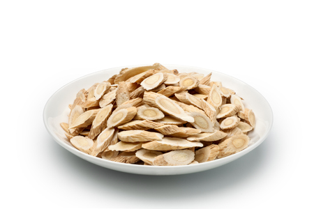 Sliced â€‹â€‹of Astragalus (Huang Qi) in a ceramic dish, isolated on white background. Chinese herbal medicine.