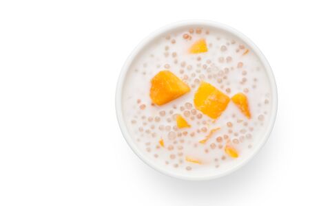 A bowl of sweet sago cream with mango and coconut milk on white background. Top view.