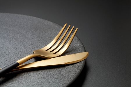 Fork and knife on a empty  black plate. Close-up.の写真素材