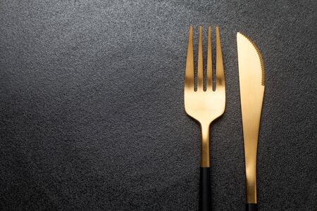 Fork and knife on a empty  black plate. Close-up.の写真素材