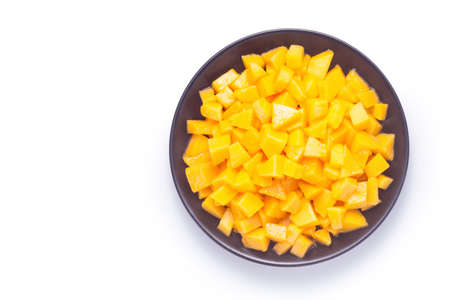 Diced mango in a black plate on white background. Top view.の写真素材