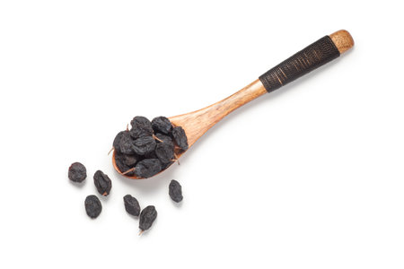 Black currant raisins in a wooden spoon. Isolated on white background.の写真素材