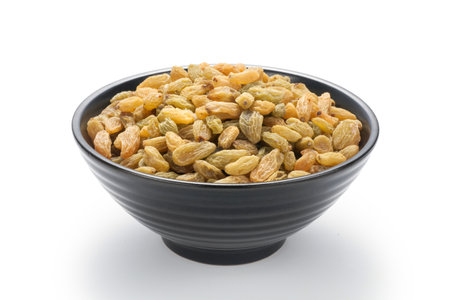 Raisins in a black bowl isolated on white background.の写真素材