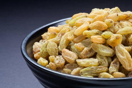 Raisins in a black bowl on black background. Close-up.の写真素材