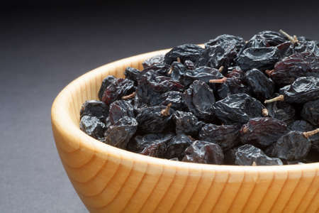 Black currant raisins in a wooden bowl. Close-up.の写真素材
