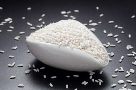 Glutinous rice in a ceramic spoon on black background.の写真素材
