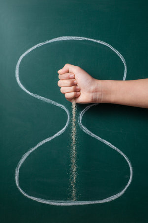 Sand falls from the hands of a little girl on a hand drawn hourglass. Time passing concept.の写真素材