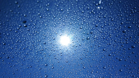 Watter drops on window with blue sky and sun lightの写真素材