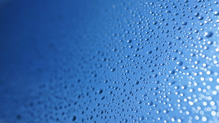 Watter drops on window with blue sky and sun lightの写真素材
