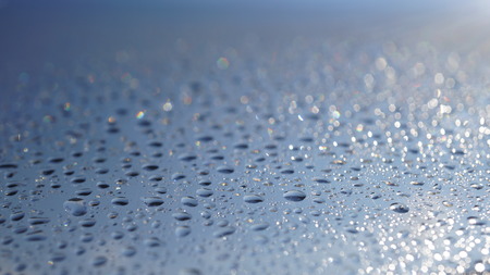 Watter drops on window with blue sky and sun lightの写真素材