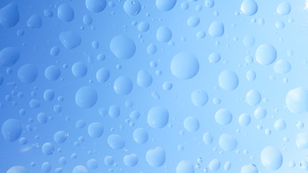 Watter drops on window with blue sky and sun lightの写真素材